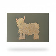 Gold foil Highland cow on a sage green greeting card held in a hand