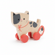 A wooden pull-along toy cat with a natural wood body, black painted face and spots, a red collar with bow, and red wheels. A round red hangtag shows the Stanley brand and the product name.