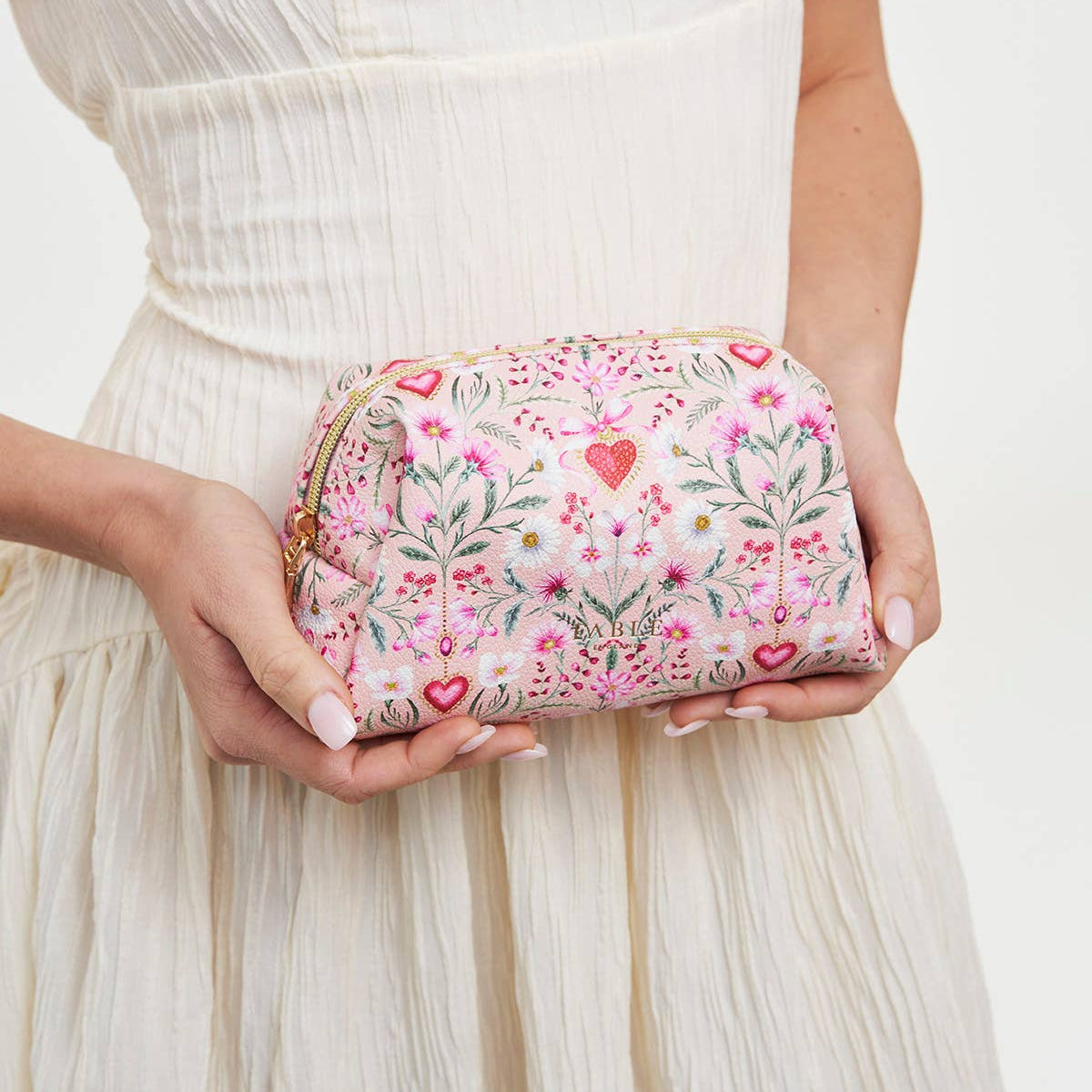 Pink floral pouch held in hand to show its compact size