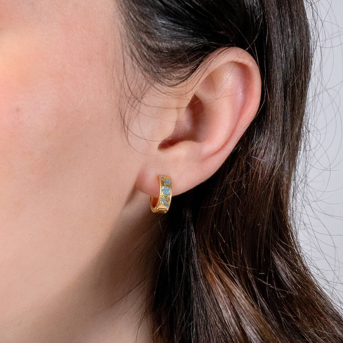 Forget-me-not hoop earring worn on ear, close-up side profile