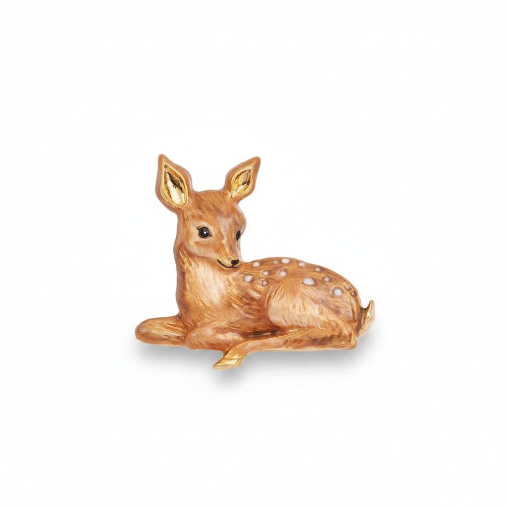 Gold enamel fawn brooch on pink surface showing detail