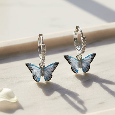 Blue Butterfly Silver Huggie Earrings on clear acrylic display stand