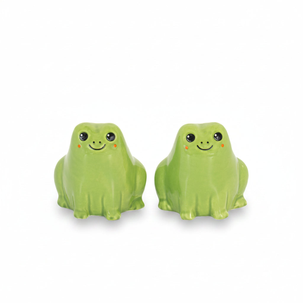 Pair of green ceramic frog salt and pepper shakers with rosy cheeks on white background