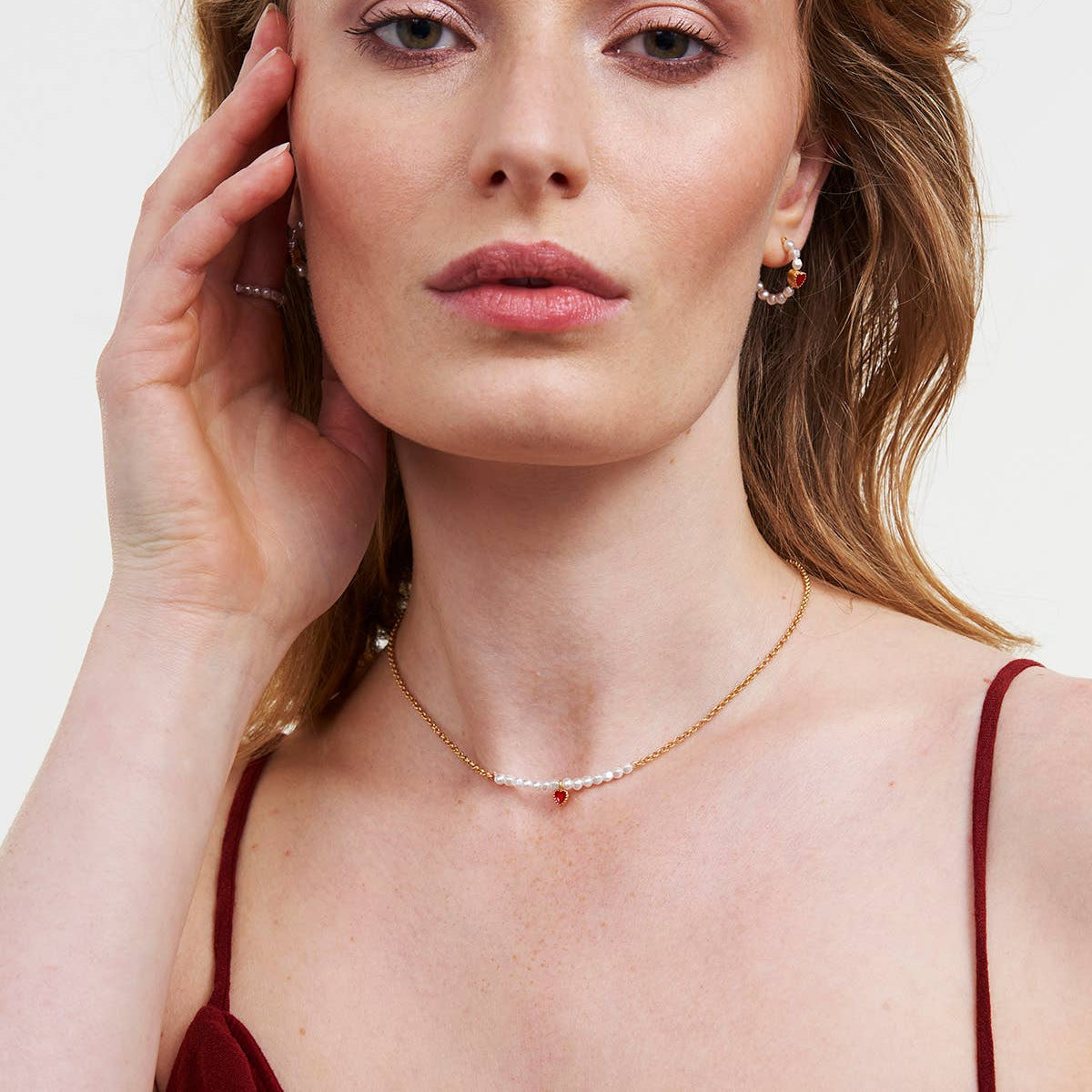 Close-up of pearl necklace with red enamel heart on model