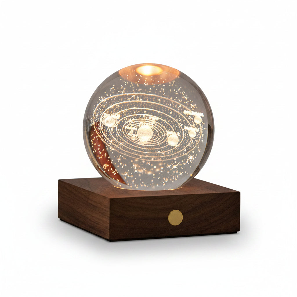 A glowing crystal sphere lamp displaying an inner solar system design, resting on a dark wooden base with a small gold circular detail, set against a dark gray background.