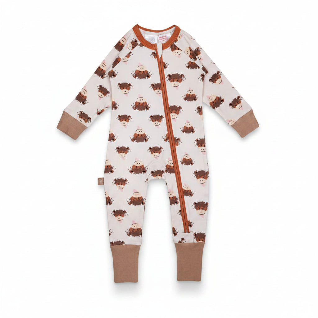 Flat lay of the Neutral Hamish Highland Cow zip-up romper against a warm-toned background, highlighting the zip and printed design.