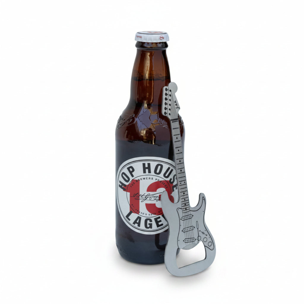 Stainless steel guitar-shaped bottle opener propped against a Hop House 13 Lager bottle, with product detailing clearly visible.