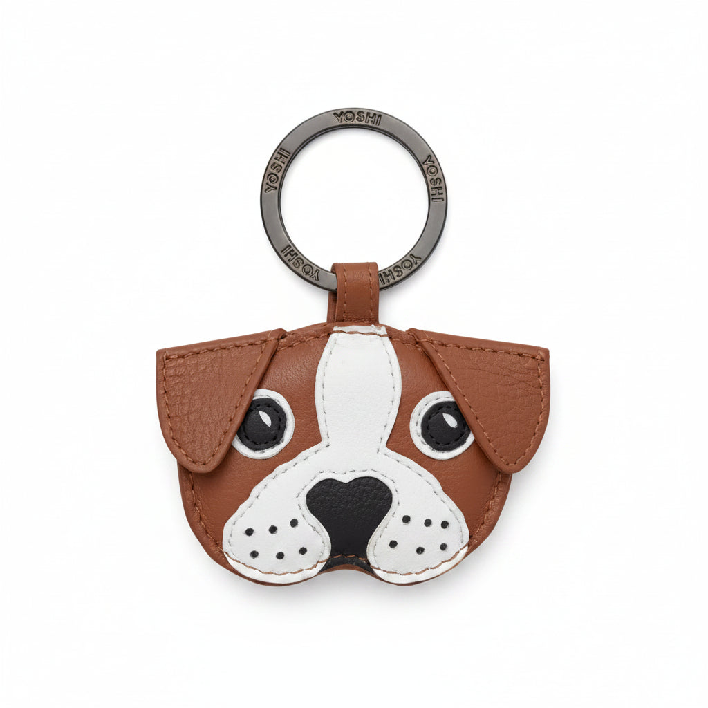 A brown and white dog-shaped leather keychain charm with a black nose and eyes, attached to a silver metal key ring engraved with 'YEAH KEYCHAIN'.