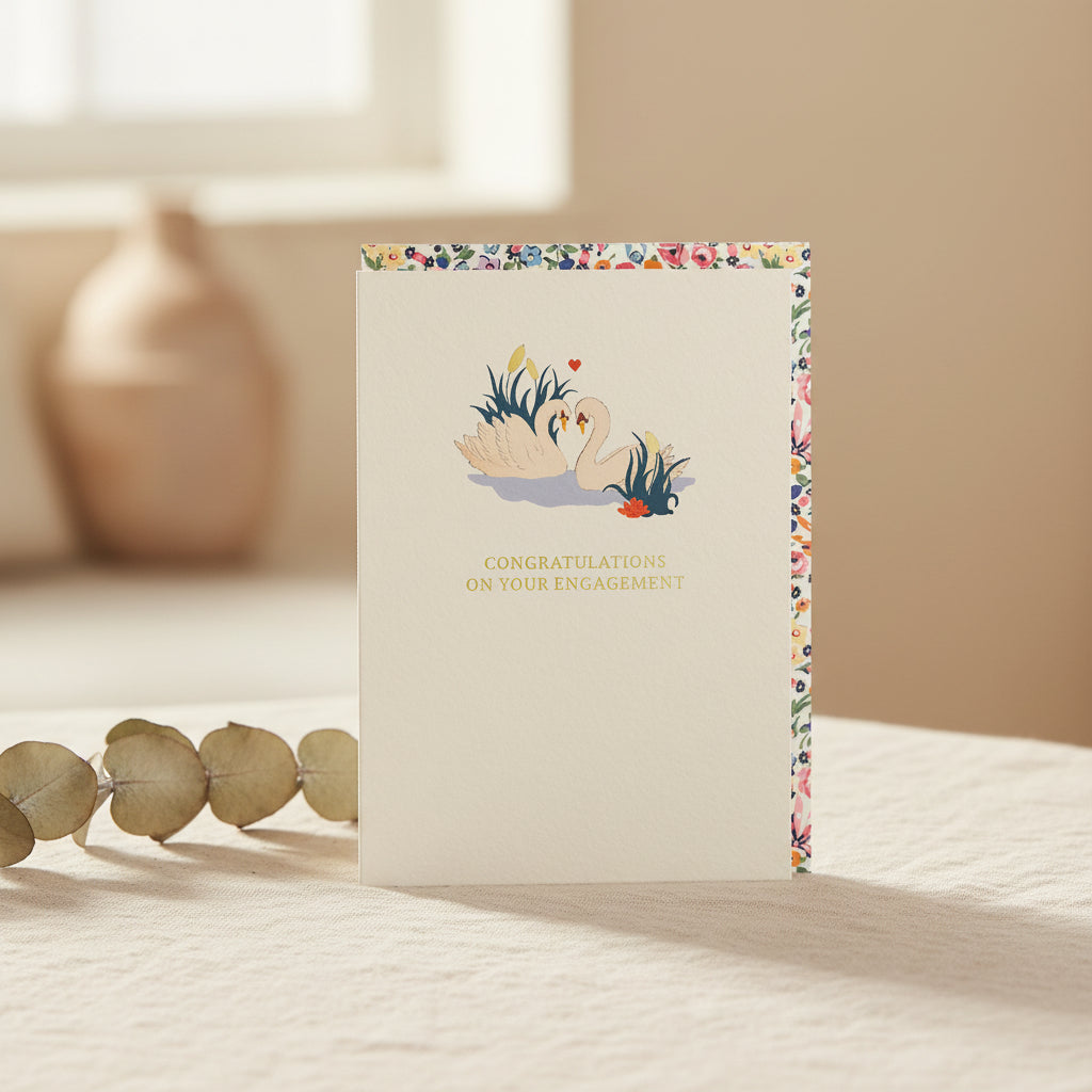 Engagement card with swan illustration and floral border on a white background