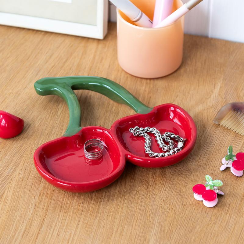 Cherry trinket dish on wooden table holding silver necklace