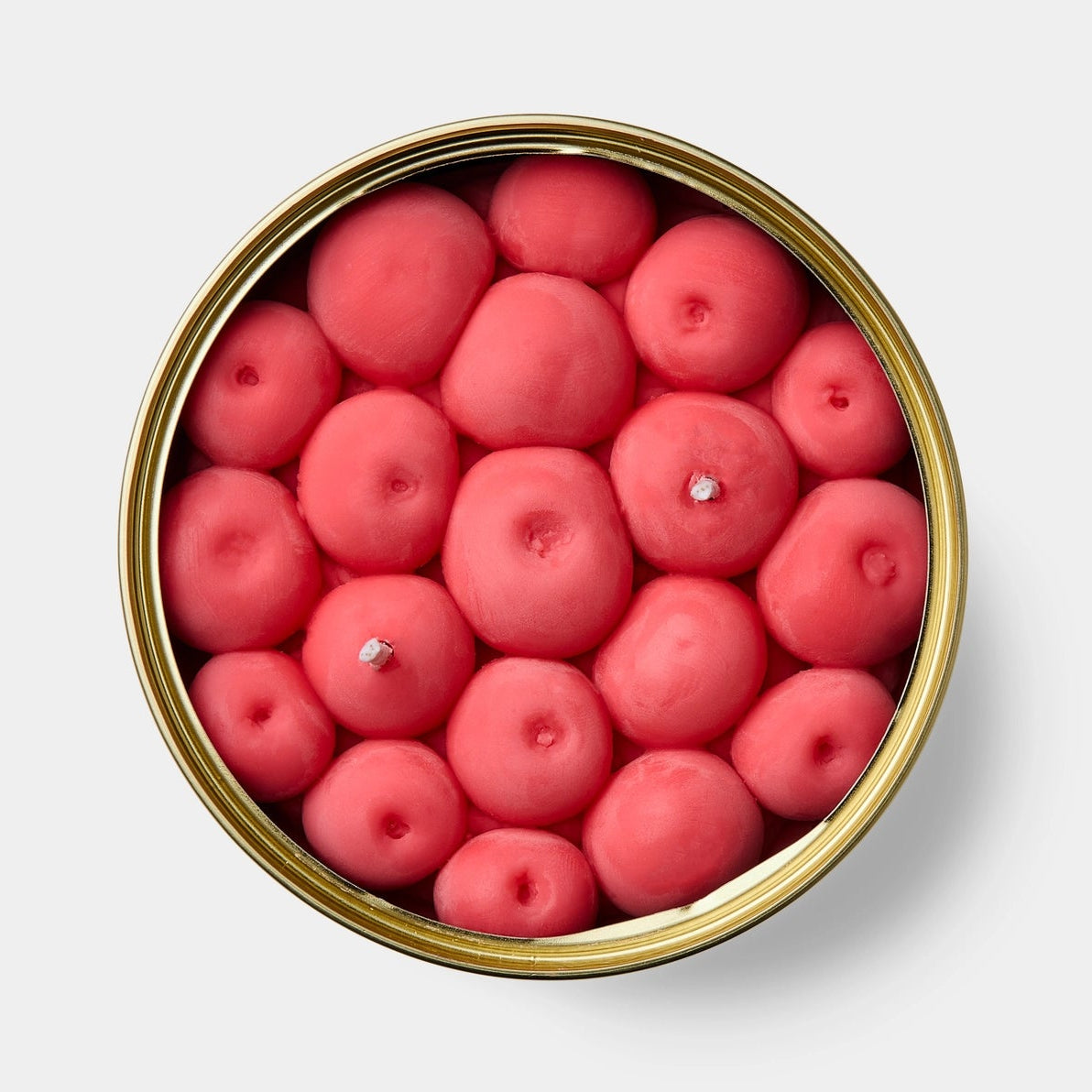Top-down view of cherry-scented candle with individual cherry-shaped wax pieces packed tightly inside gold tin.