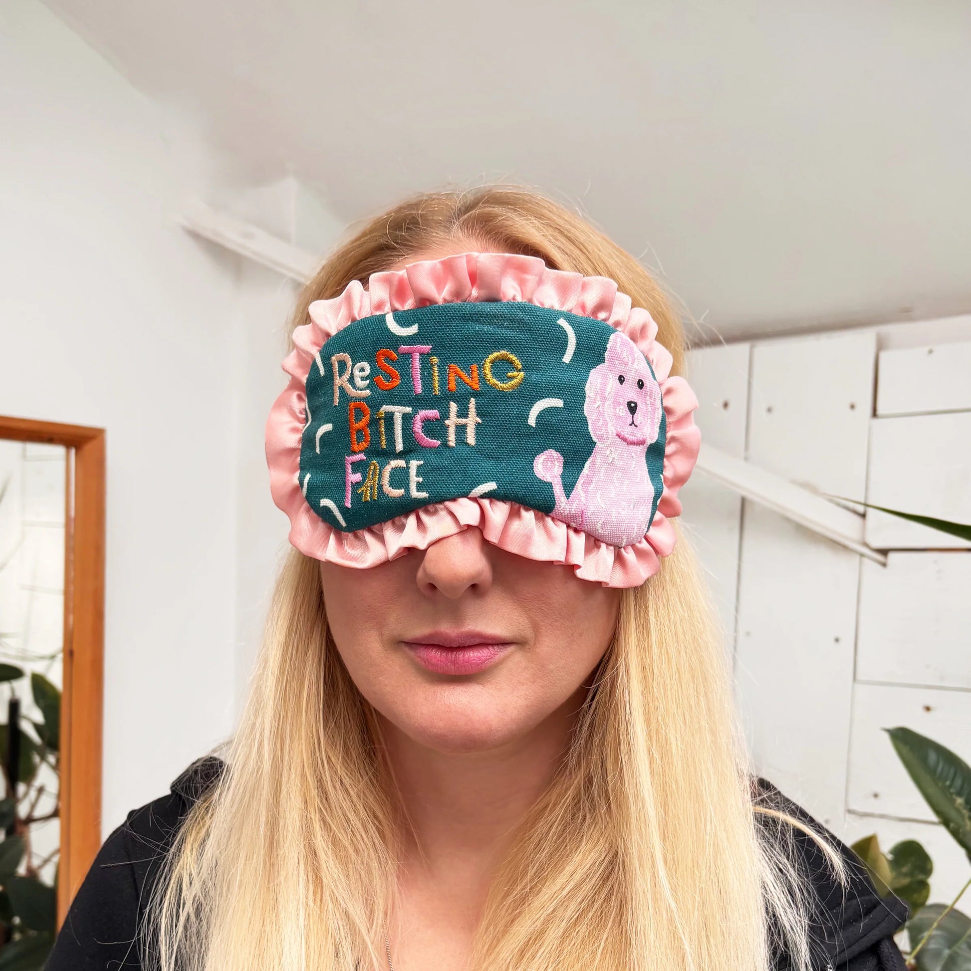 Woman wearing Resting Bitch Face eyemask with embroidered dog and text.