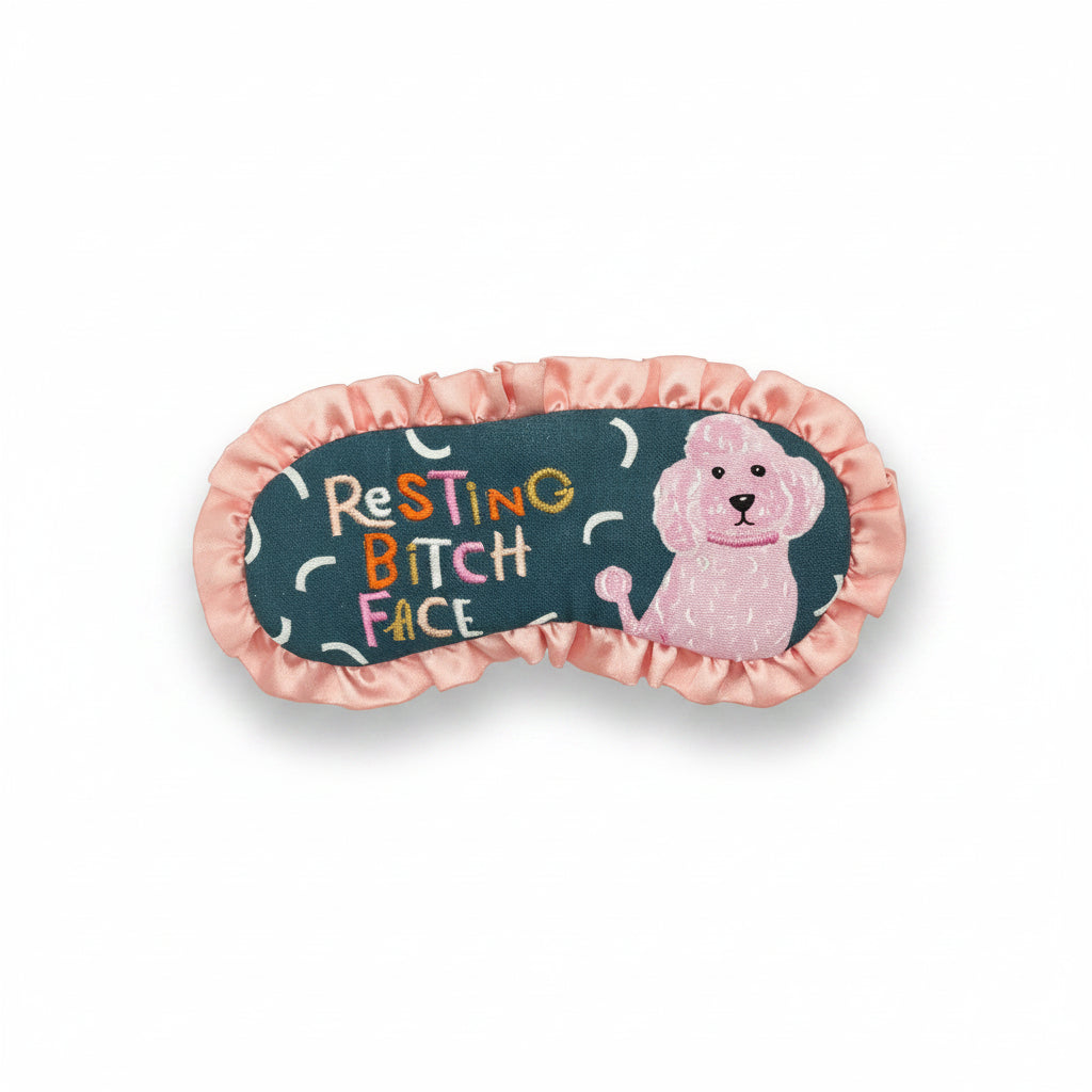 Flat lay of Resting Bitch Face eyemask with pink satin frill and green cotton front.