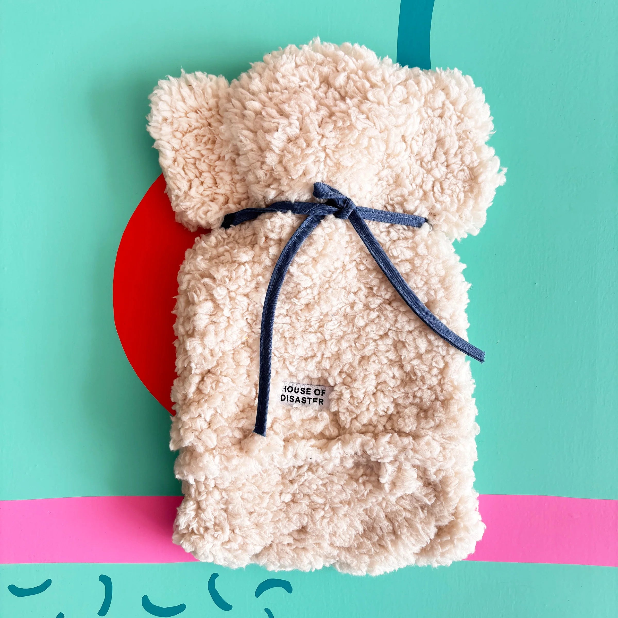 Back of fluffy dog hot water bottle tied with blue strap.