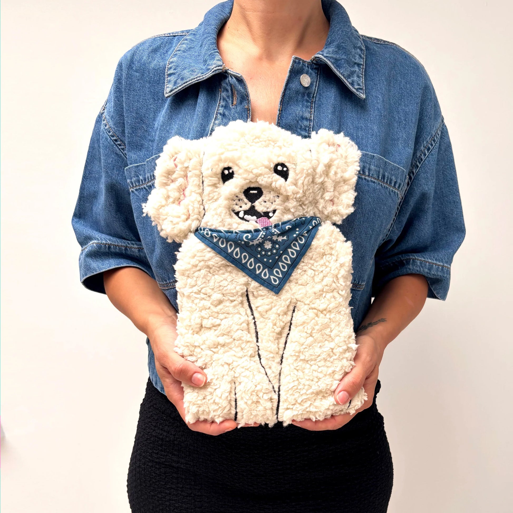 Model holding soft boucle dog hot water bottle in front view.