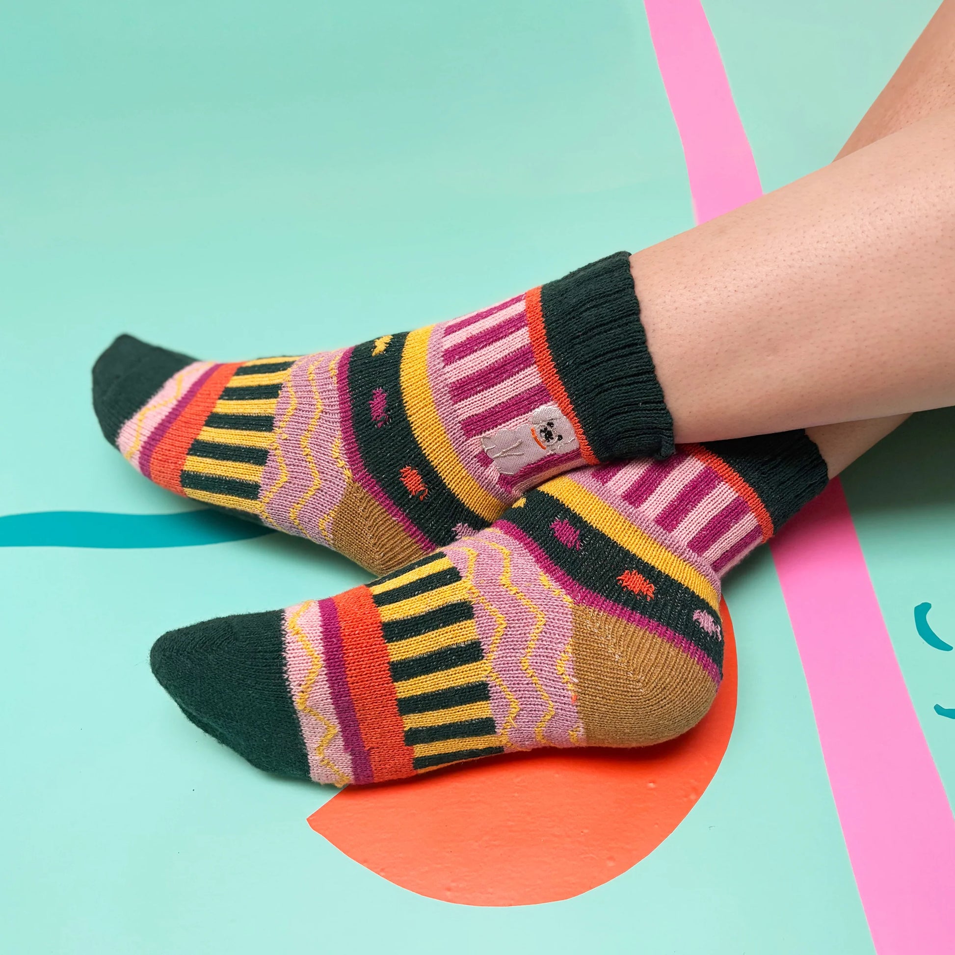 Model wearing colourful Doghouse Fair Isle Socks against bright background.