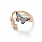 Enamel Blue Butterfly Ring with gold-plated band and hand-painted blue butterfly charm beside clear crystal gems.
