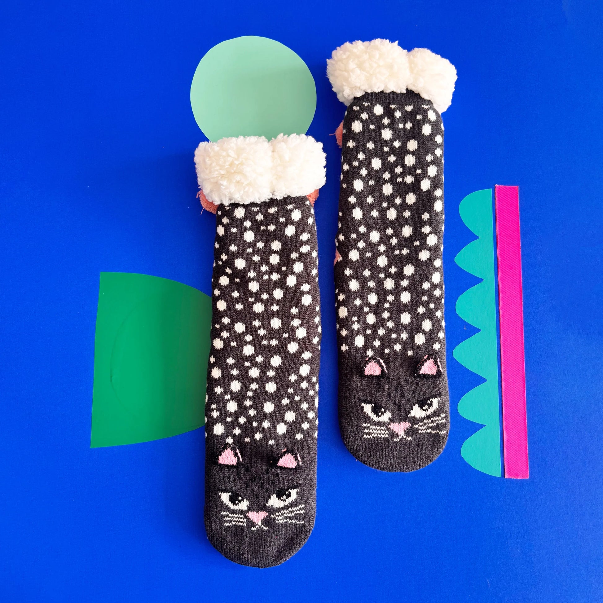 Feline Cat Face Slipper Socks with polka dot pattern and fluffy cuff on blue background.