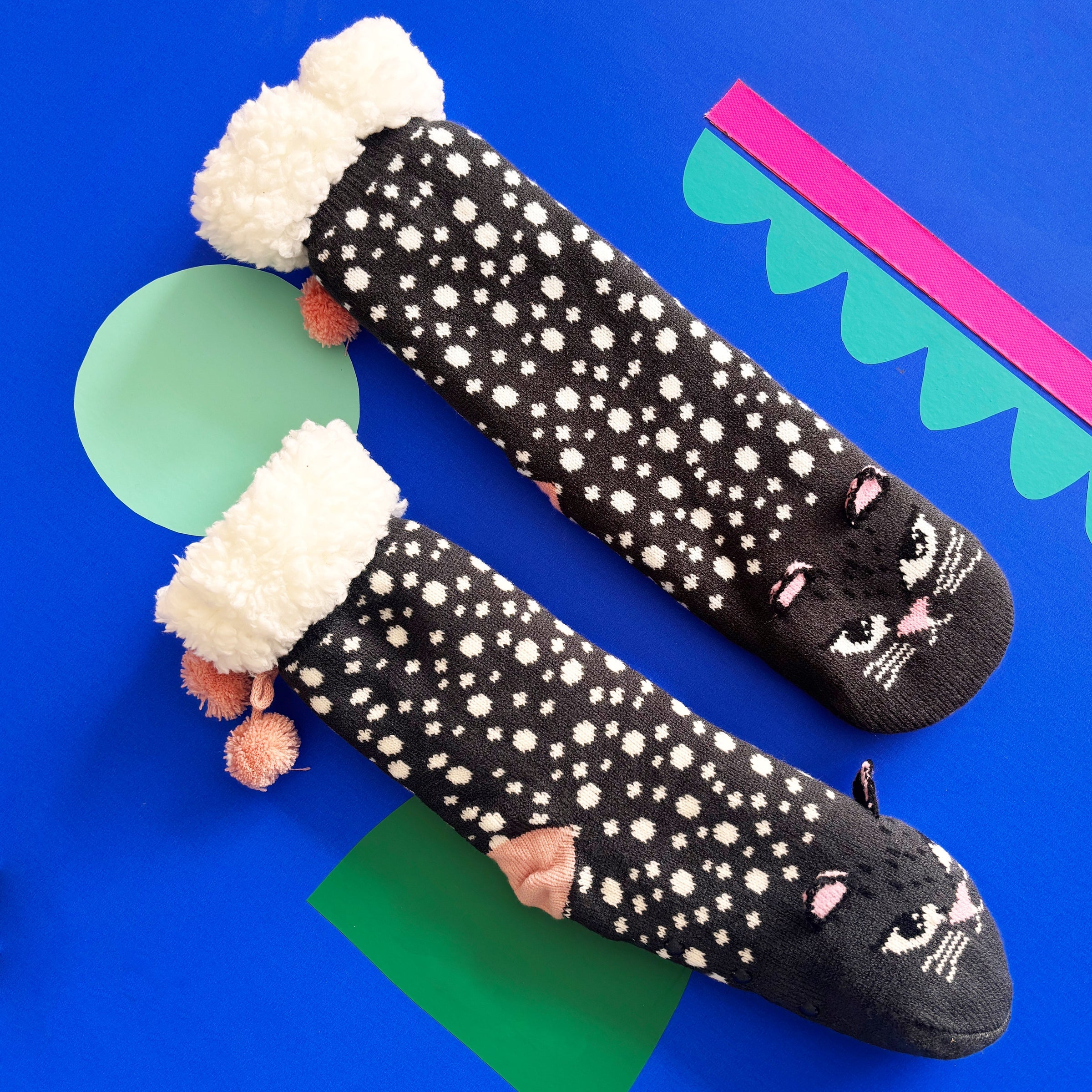 Side view showing embroidered cat design and orange heel pom poms.
