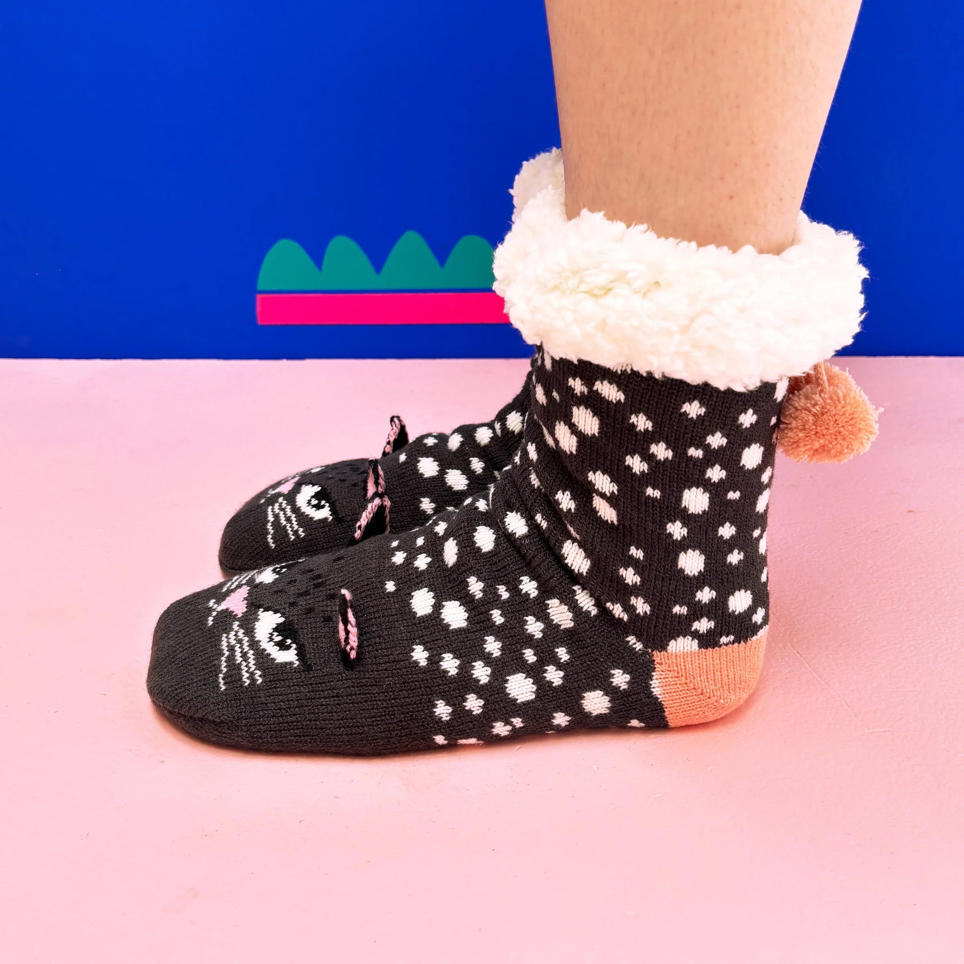Model wearing Feline Cat Face Slipper Socks on pink background.