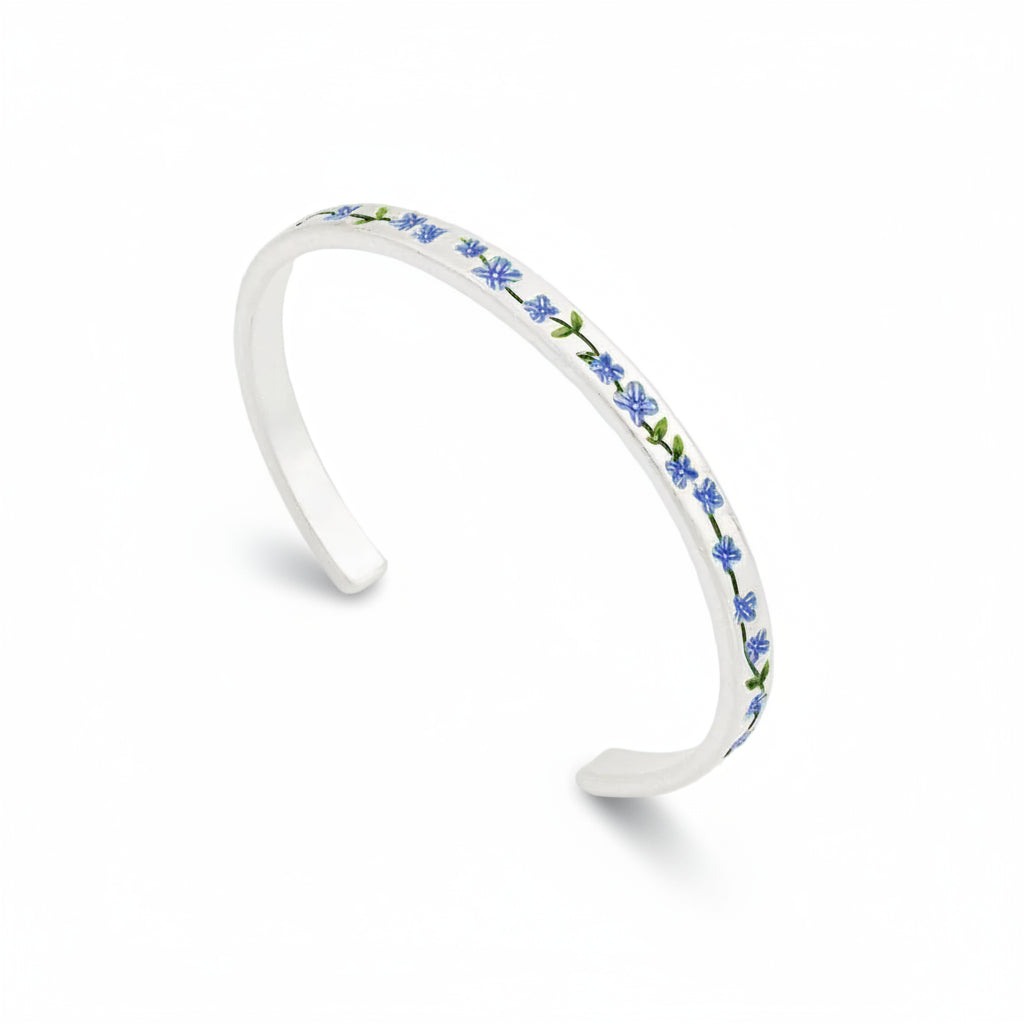 Sterling silver bangle with delicate forget-me-not flower charm on plain white background.