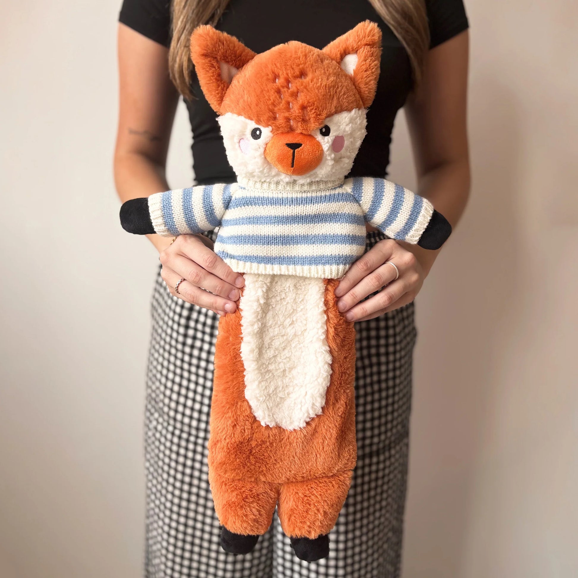 Person holding soft fox hot water bottle with cosy knitted jumper.