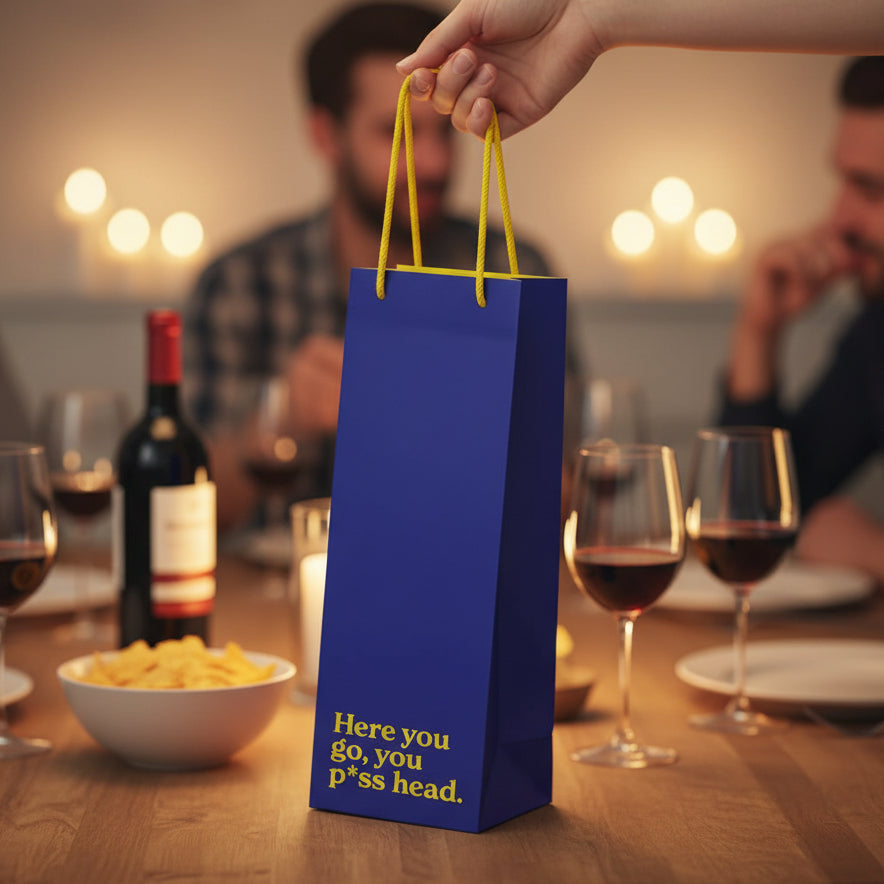 Navy bottle gift bag held at dinner table with wine glasses