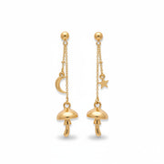 Gold mushroom drop earrings with crescent moon and star charms, displayed on a green rustic surface with moss decoration.