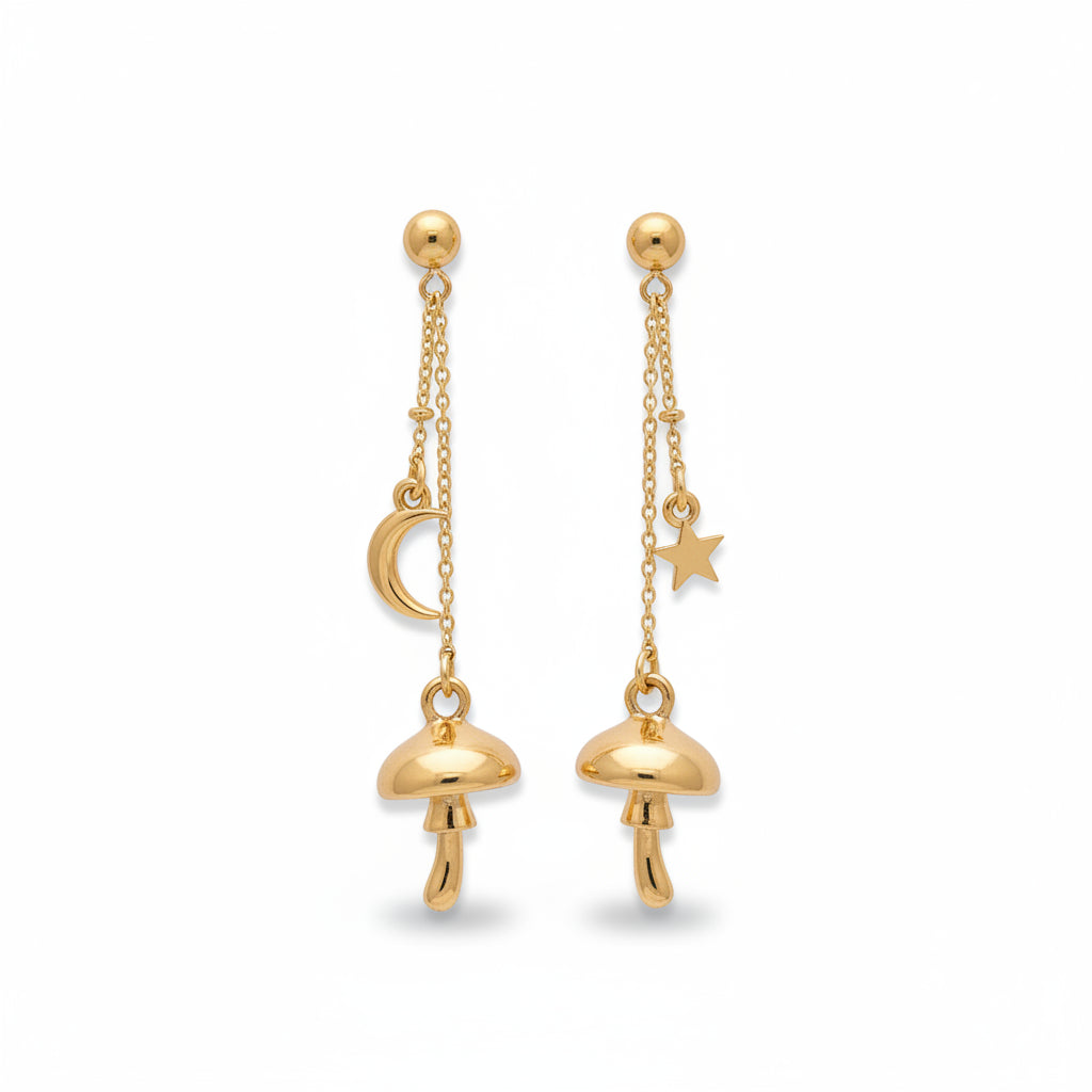 Gold mushroom drop earrings with crescent moon and star charms, displayed on a green rustic surface with moss decoration.