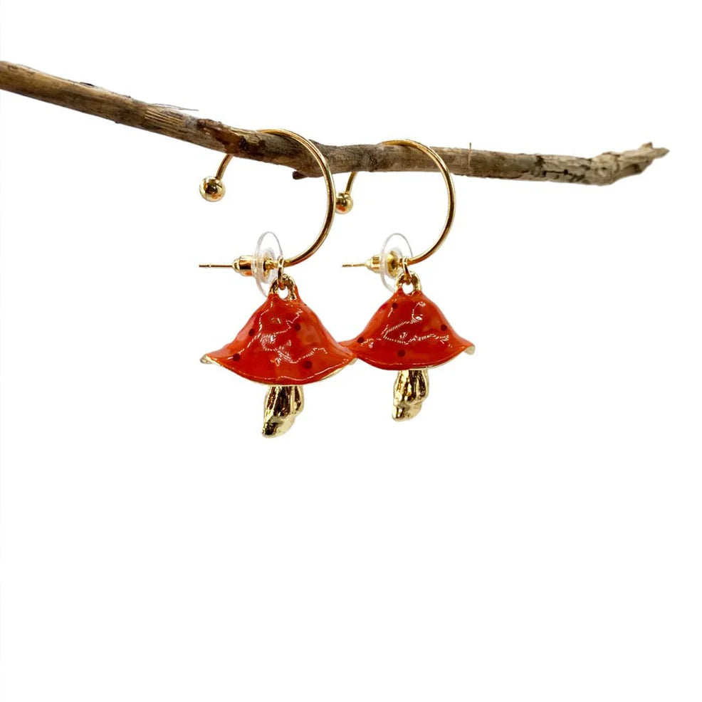 Studio image of Forage Red Mushroom Earrings hanging on branch, clearly showing glossy red caps and gold-plated stems with butterfly backs.