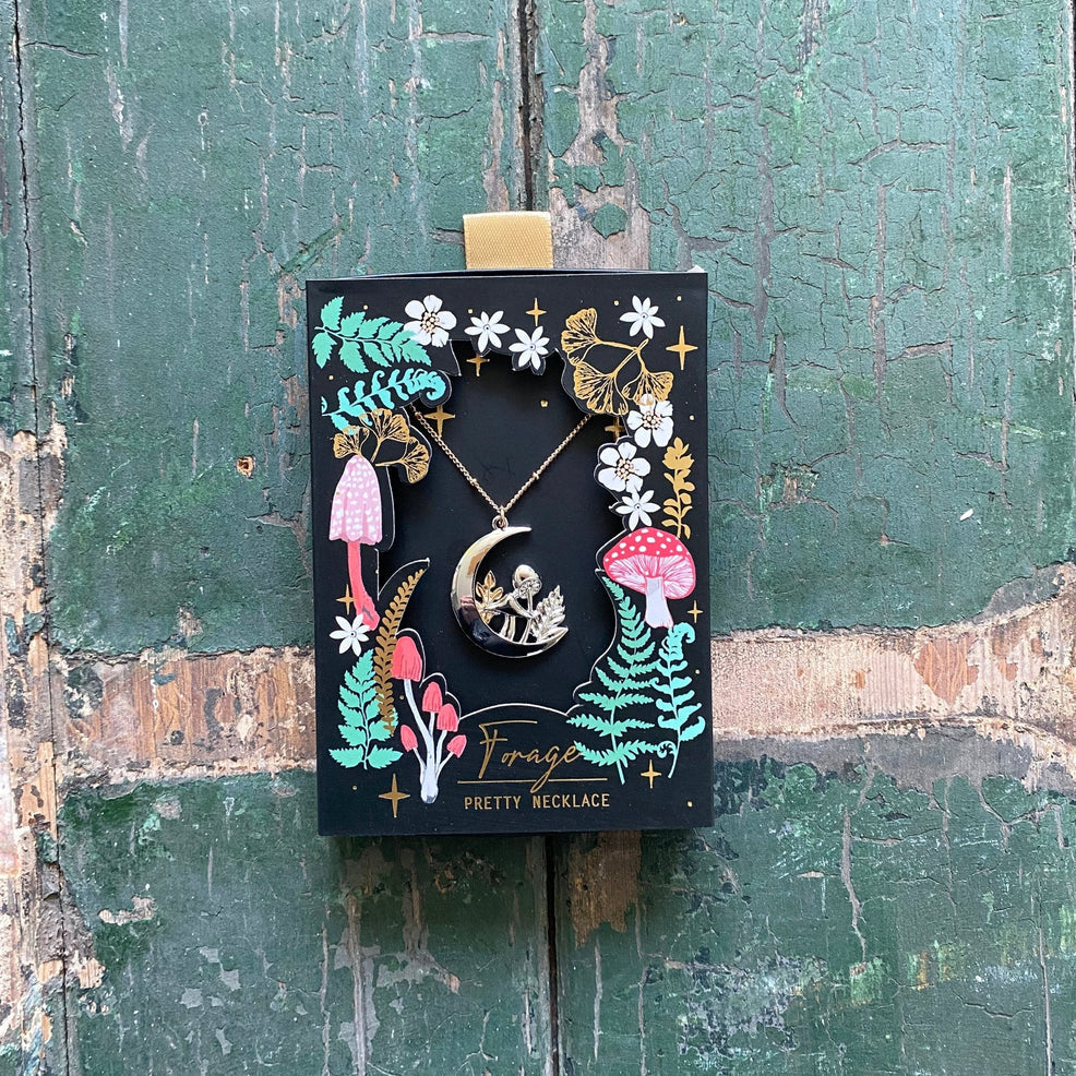 Forage Moon Necklace packaged in black illustrated gift box with vibrant mushrooms, ferns, and gold foil accents, ideal for gifting.