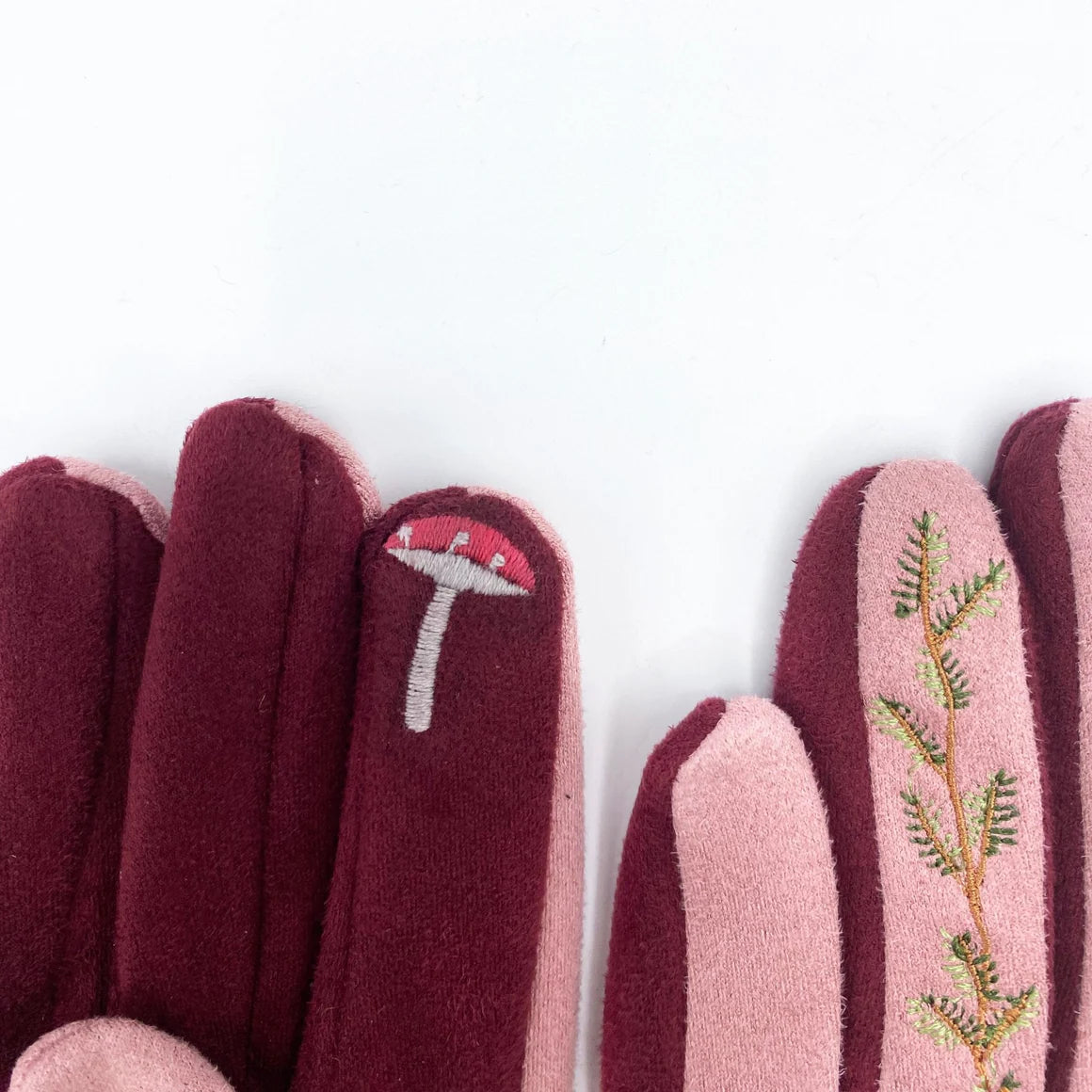 Artful flat lay of navy blue gloves with pink trim and embroidered hedgehog design.