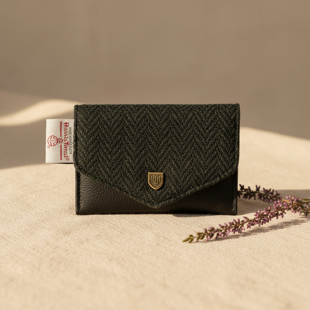 A small black and gray herringbone patterned wallet with a black textured flap and a gold shield logo, shown on a white background with a brand tag visible on the left.