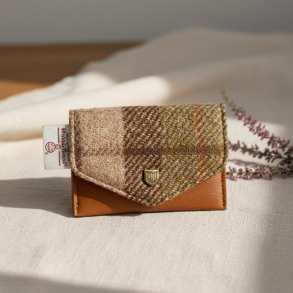 A small fold-over wallet in a brown and beige plaid tweed fabric with a solid brown leather base and a small gold crest logo on the front, shown on a white background.
