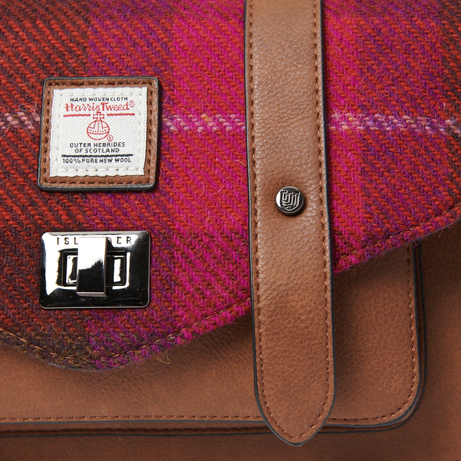 Close-up of Fuchsia Red Tartan Harris Tweed® satchel highlighting woven texture, Harris Tweed® label, and tan leather trim.