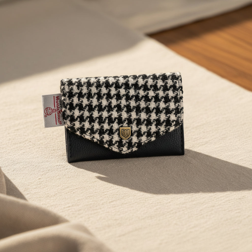 Black and white houndstooth patterned wallet with a brand tag on a white background