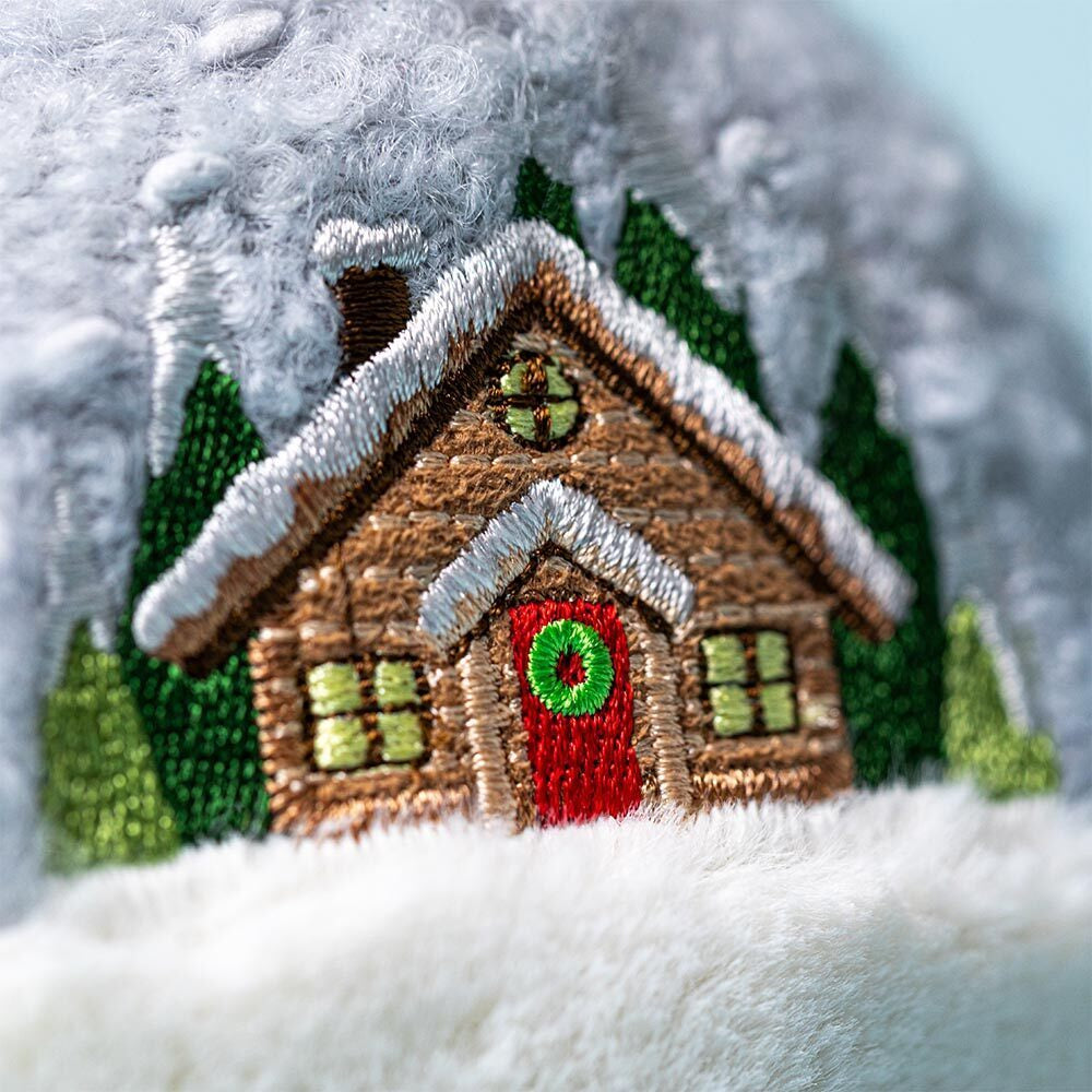 Close-up of Jellycat Snow Globe embroidery showing snowy cabin and green trees.