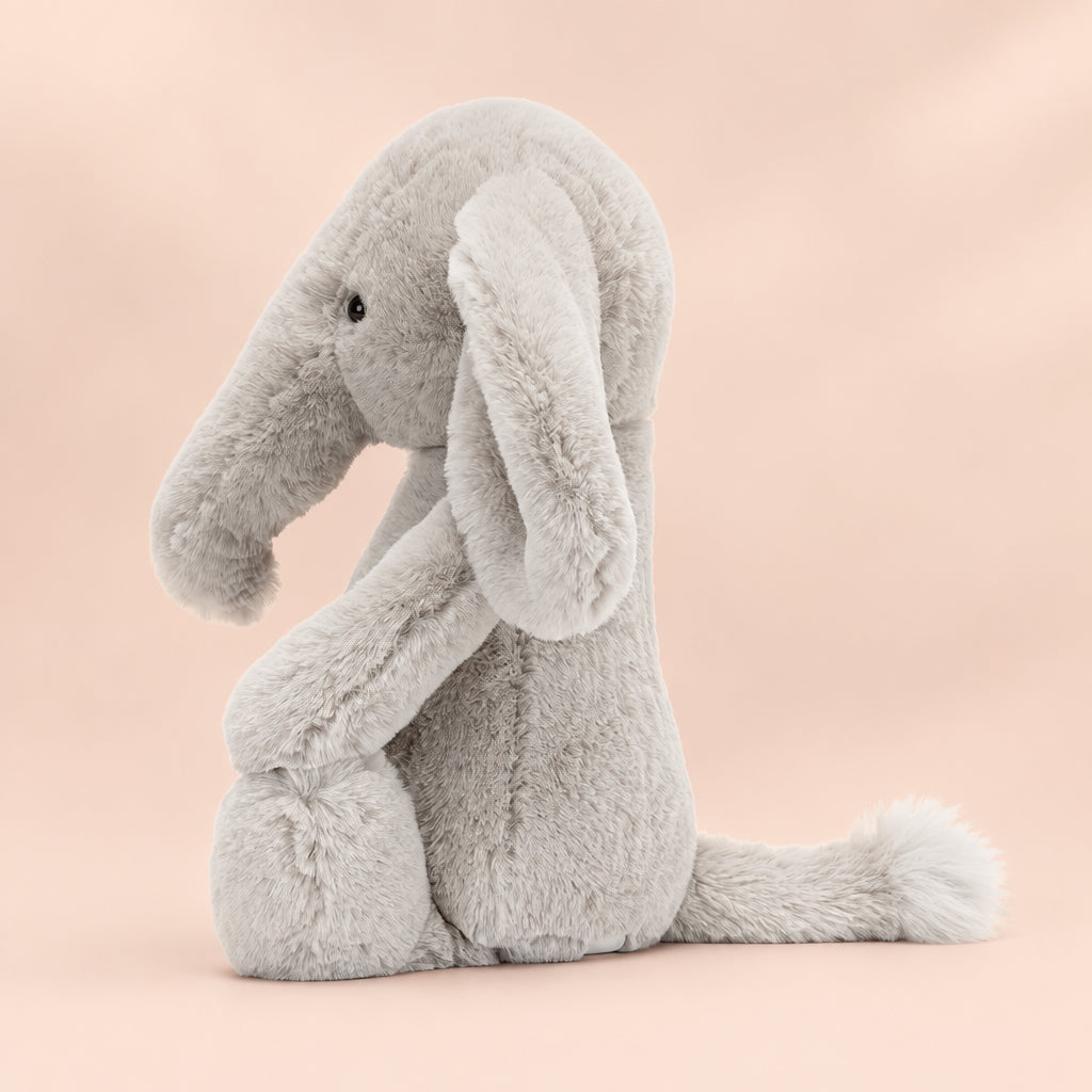 Side profile of Jellycat Bashful Luxe Elephant Thuddeus showing floppy limbs, curved trunk, and soft textured fabric.