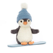 Jellycat Peanut Penguin Snowboarding soft toy wearing a blue pom-pom hat standing on a blue snowboard.