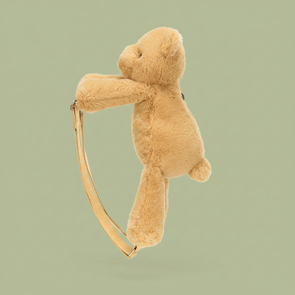 Side profile of Jellycat Smudge Bear Backpack showing soft plush texture and strap shape.