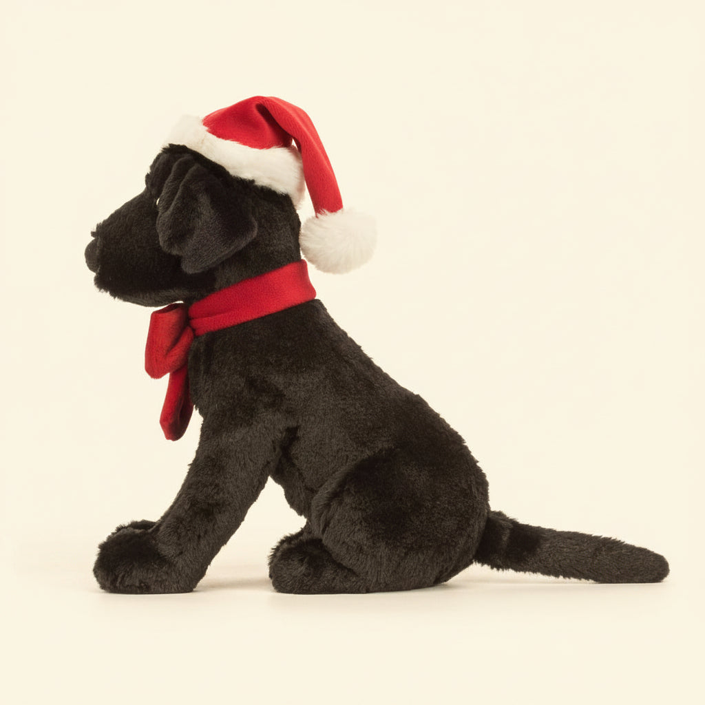 Side view of Jellycat Pippa Labrador soft toy sitting upright with festive hat.