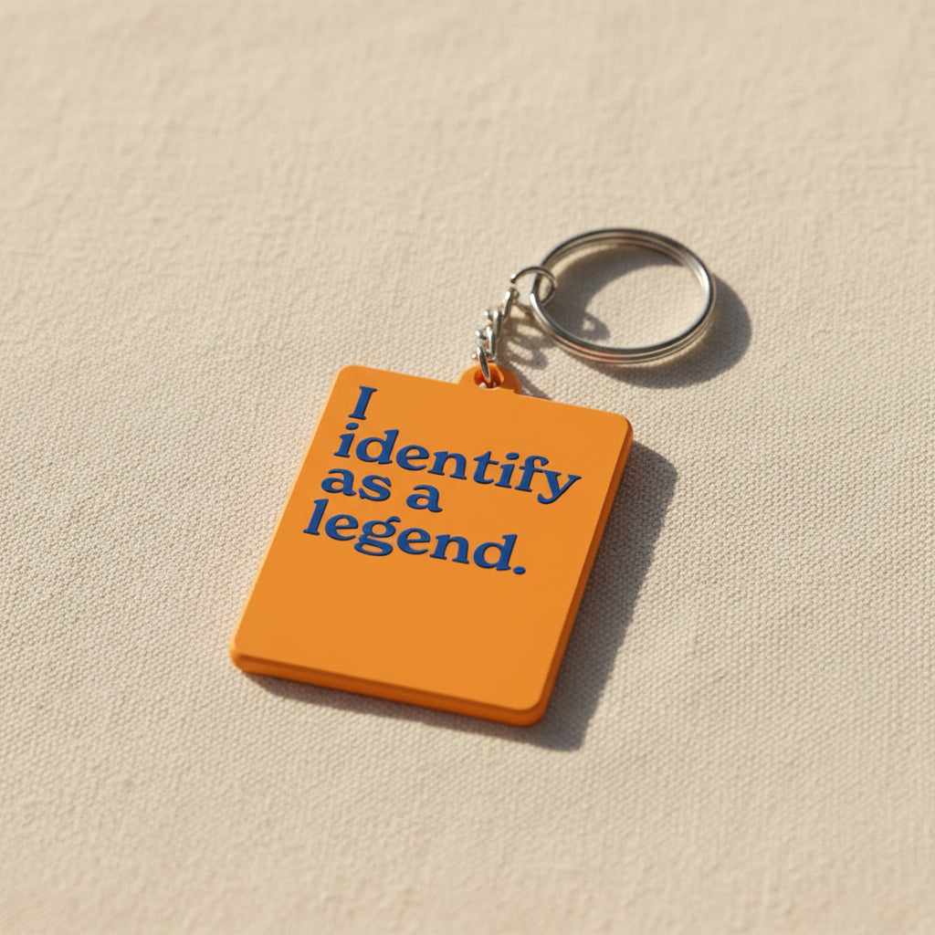 Orange keychain with blue text 'I identify as a legend' on a white background