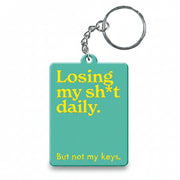 Green keyring with the words losing my shit daily in yellow printed across the front. 