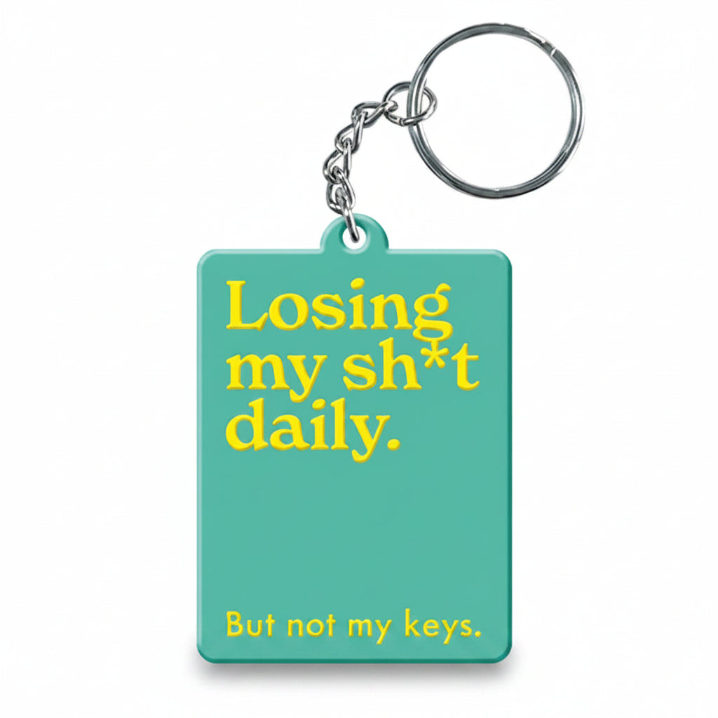 Green keyring with the words losing my shit daily in yellow printed across the front. 