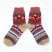 Flat lay of a pair of Fair Isle Moomin socks with Little My embroidery, in red, pink, and biscuit tones with navy and cream accents.