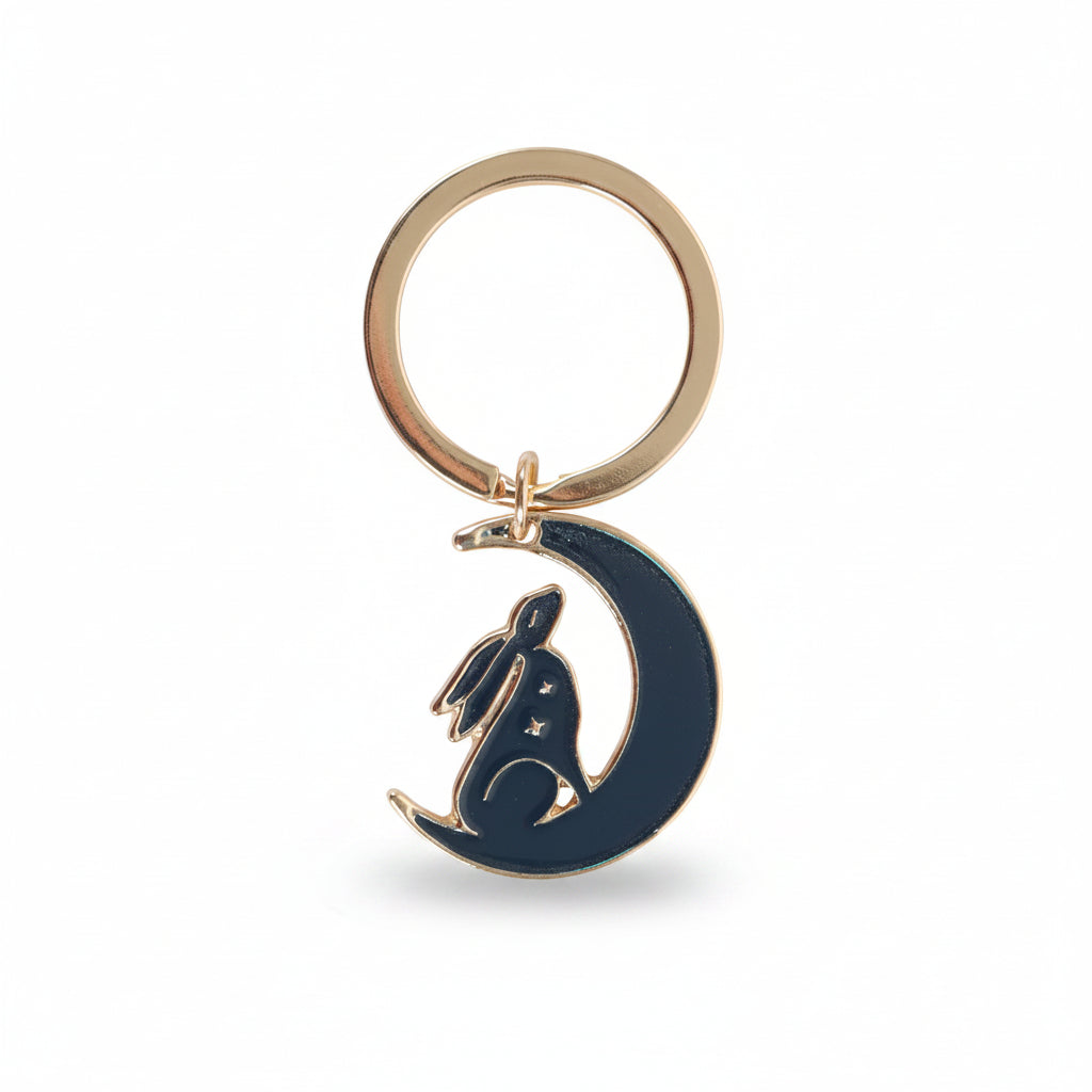 Keyring with navy hare sitting in crescent moon on backing card.
