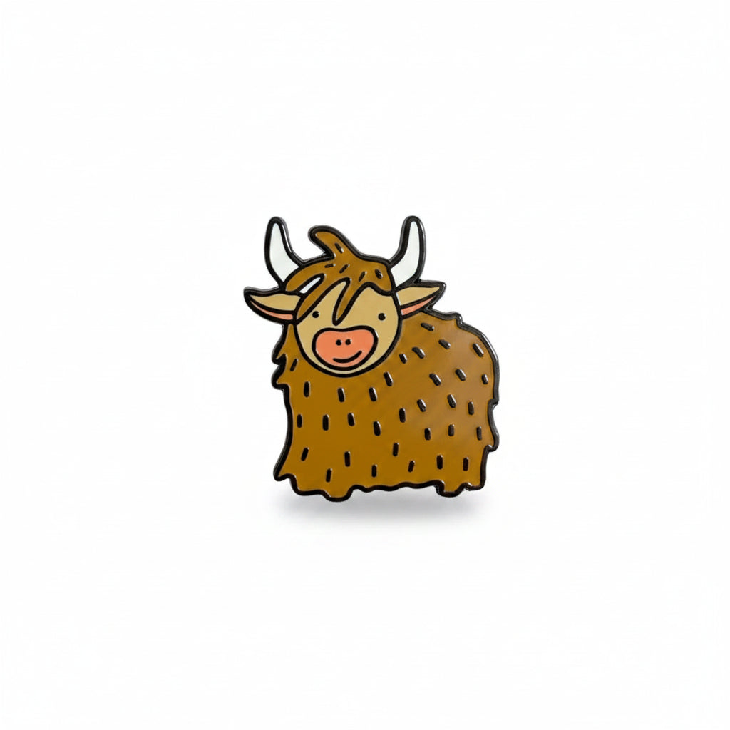 A small cartoon-style cow pin or charm being held between two fingers against a plain white background.
