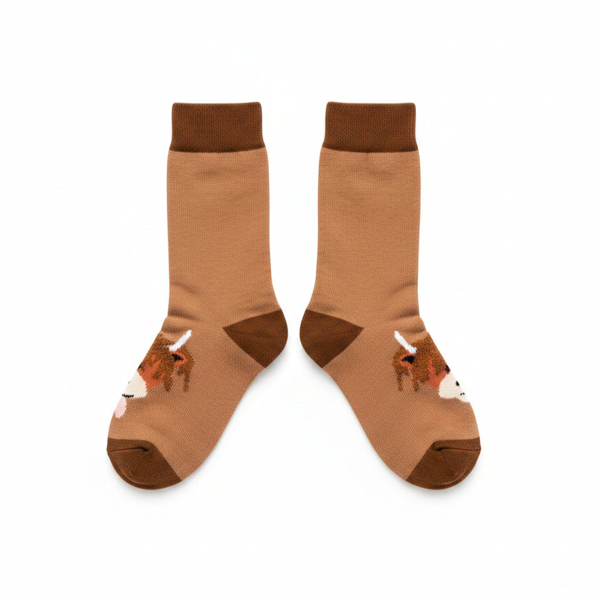 A pair of brown crew socks with a cow face graphic on the sole, worn on feet against a plain white background.