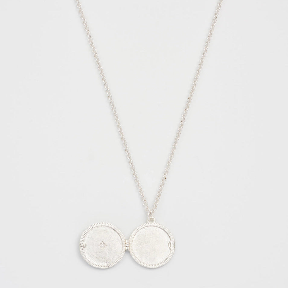 Open silver locket necklace with enamel moon and star design.