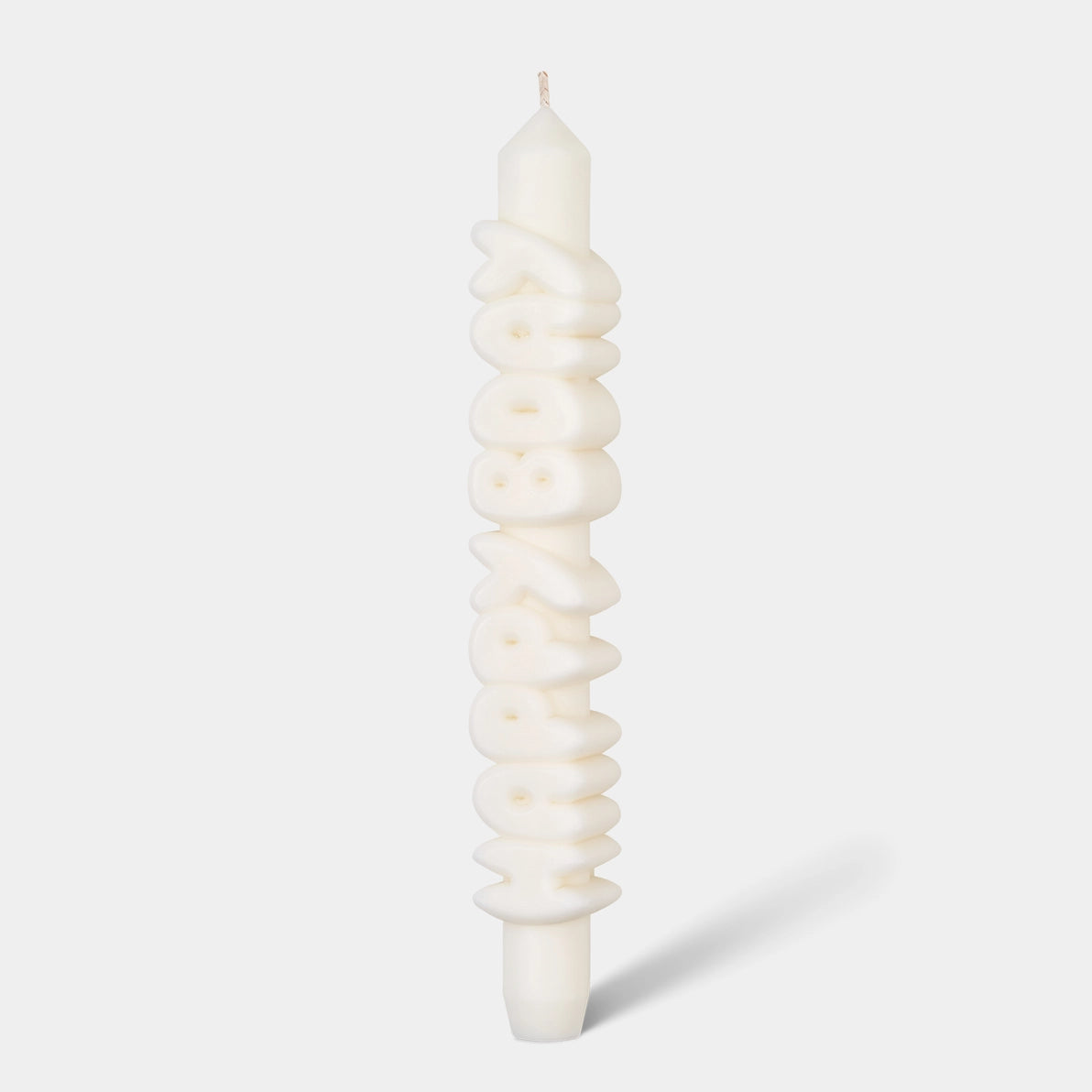 Studio image of a 9-inch white taper candle with bold, sculpted “HAPPY BDAY” lettering running vertically, handmade from eco-friendly wax blend.